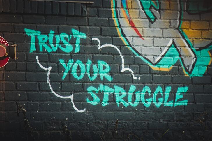Trust your struggle written in grafitti on a brick wall.