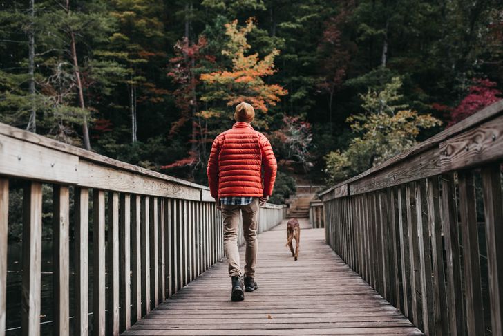 A man exercising by walking his dog through a trail